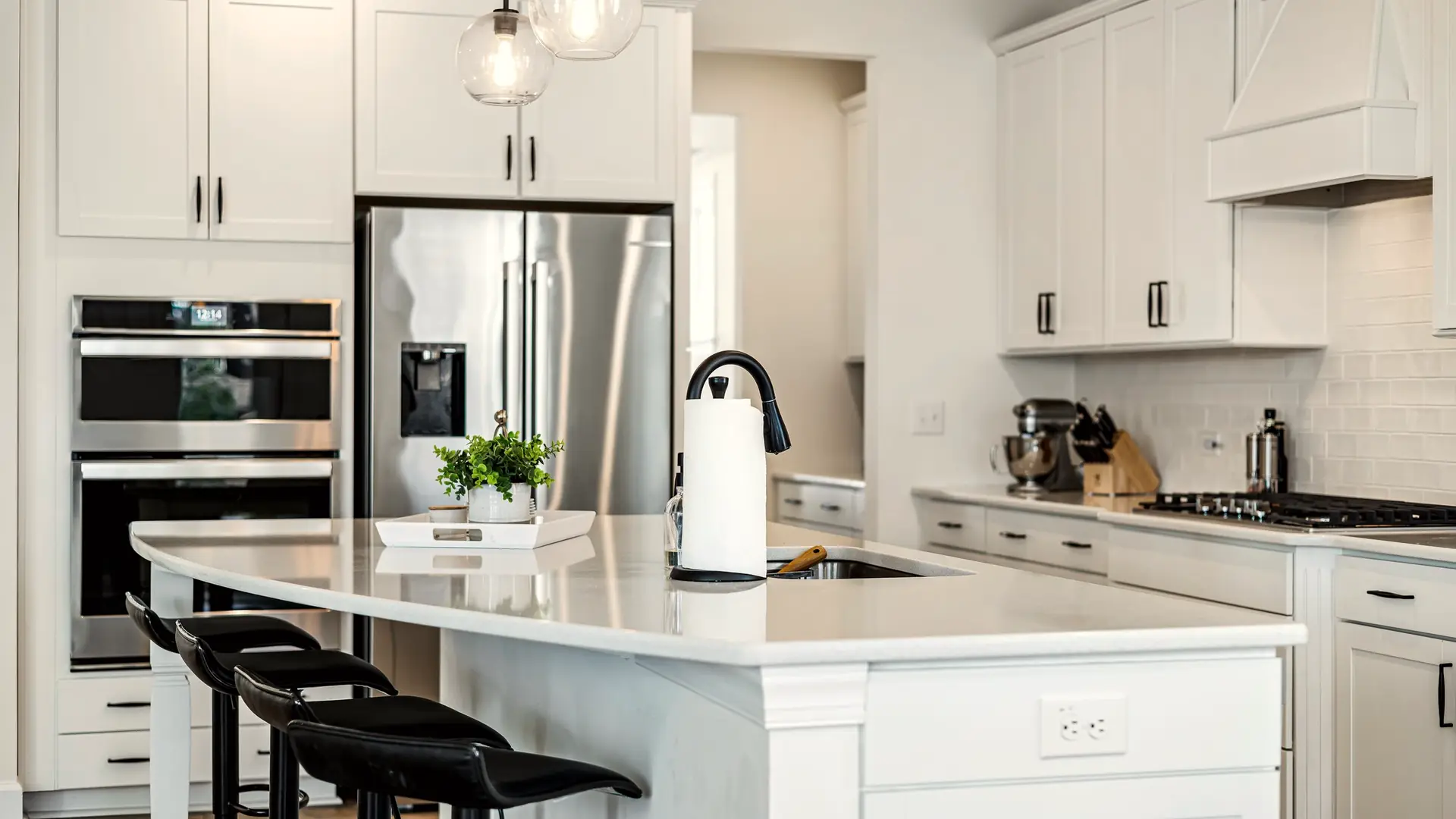 Finished white kitchen with shaker cabinets, a quartz island and glass pendant lights