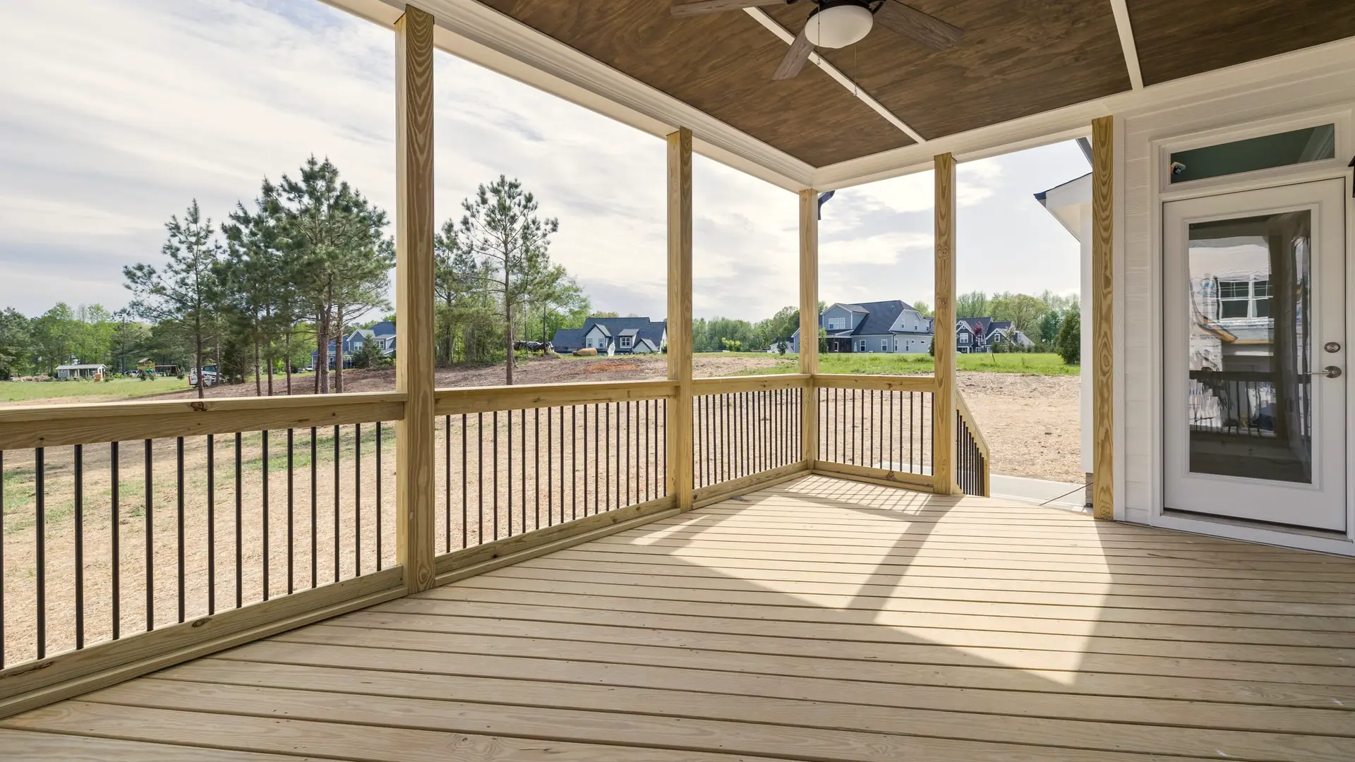 New covered deck with a stained ceiling, ceiling fan and black metal balusters