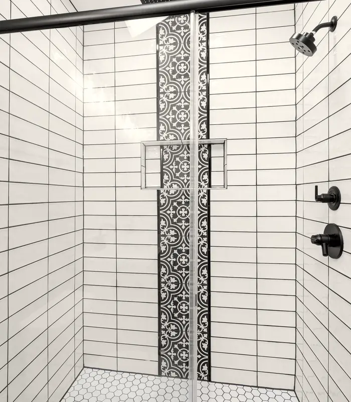Finished walk-in shower with white subway tile, a patterned tile stripe and a recessed niche