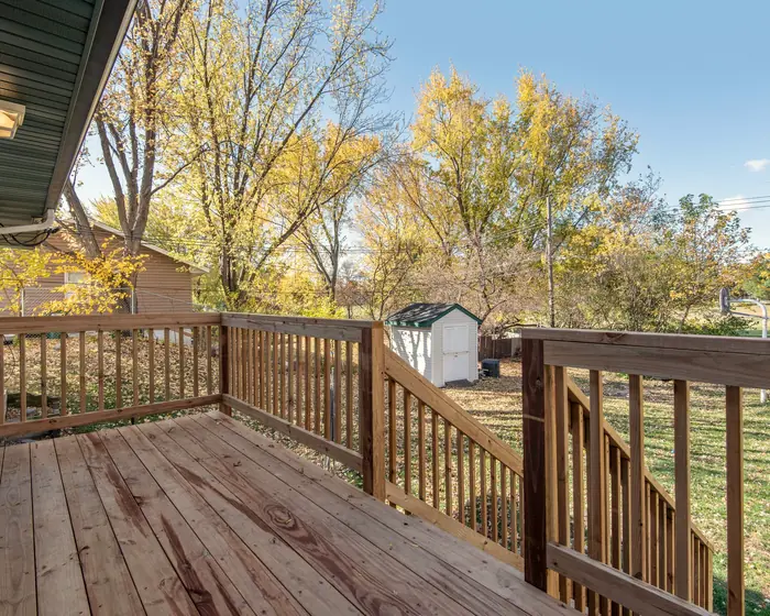 Wood deck with a stair down to a backyard of yellow fall trees
