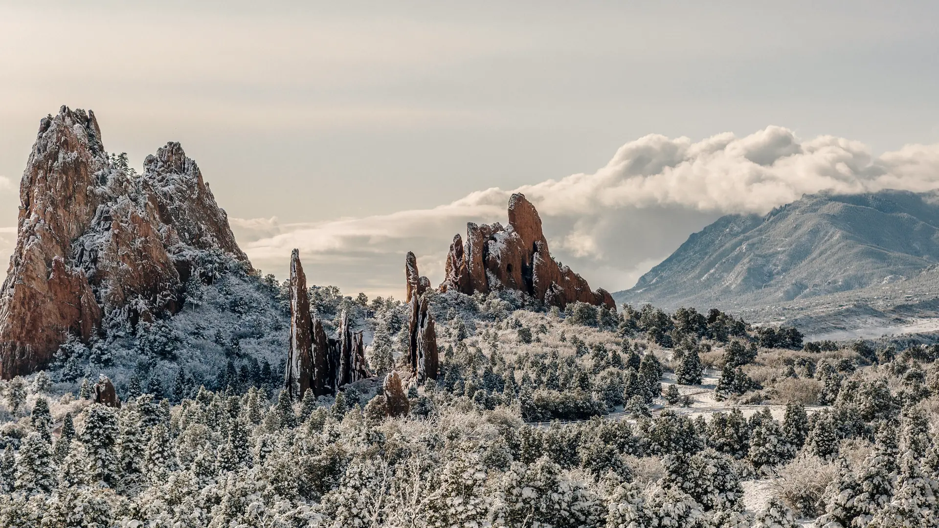 Garden of the Gods rock formations under fresh snow, with Pikes Peak behind
