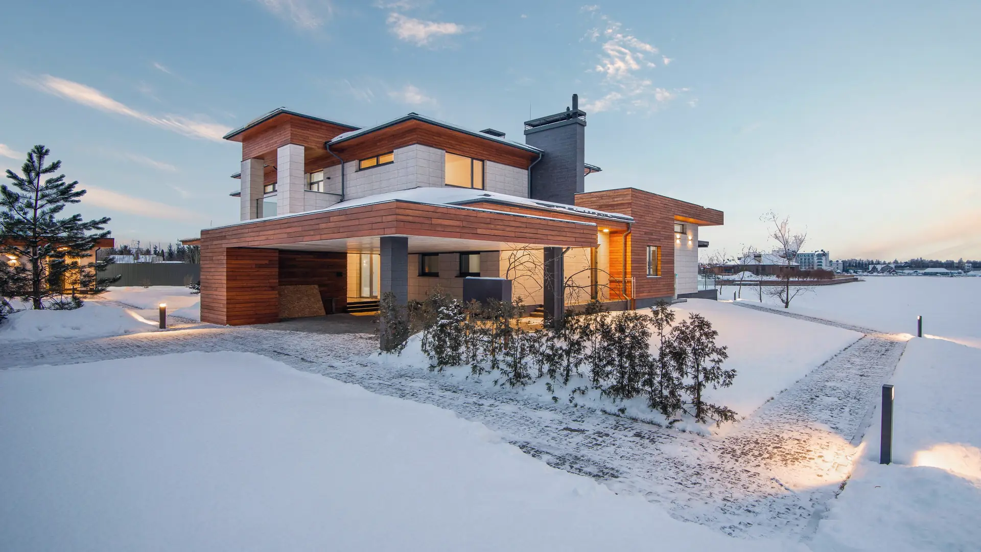 House in fresh snow at dusk with its windows lit