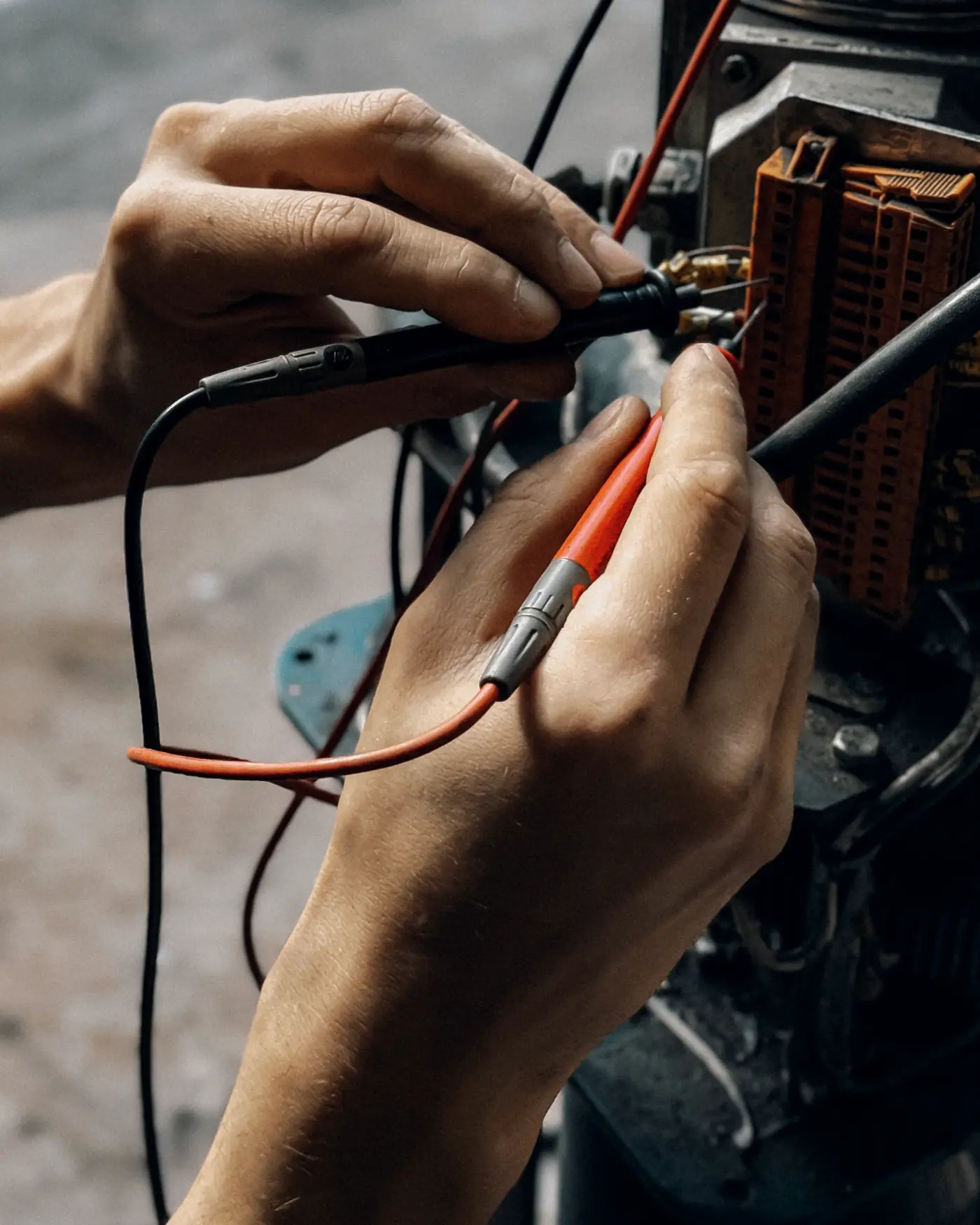 Technician's hands testing a motor's wiring with meter probes