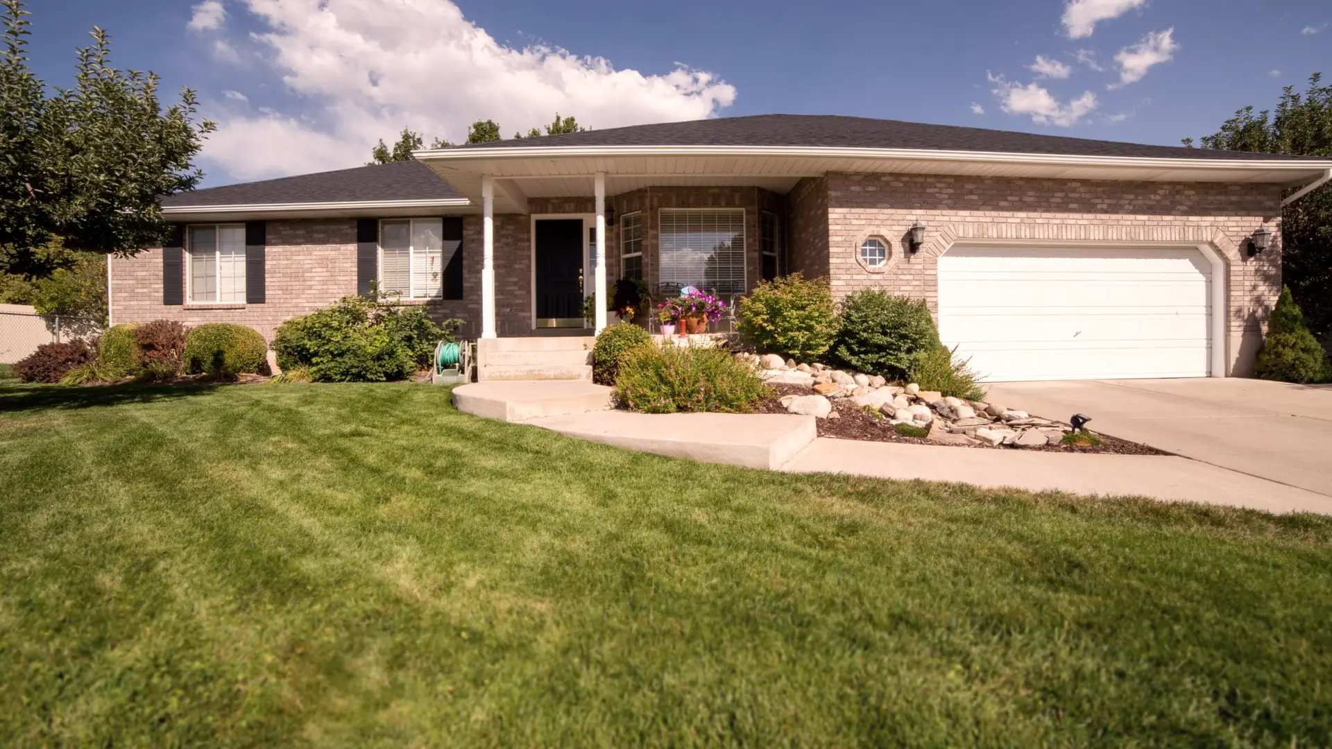 Brick ranch house with a freshly mowed, striped front lawn and rock-edged beds