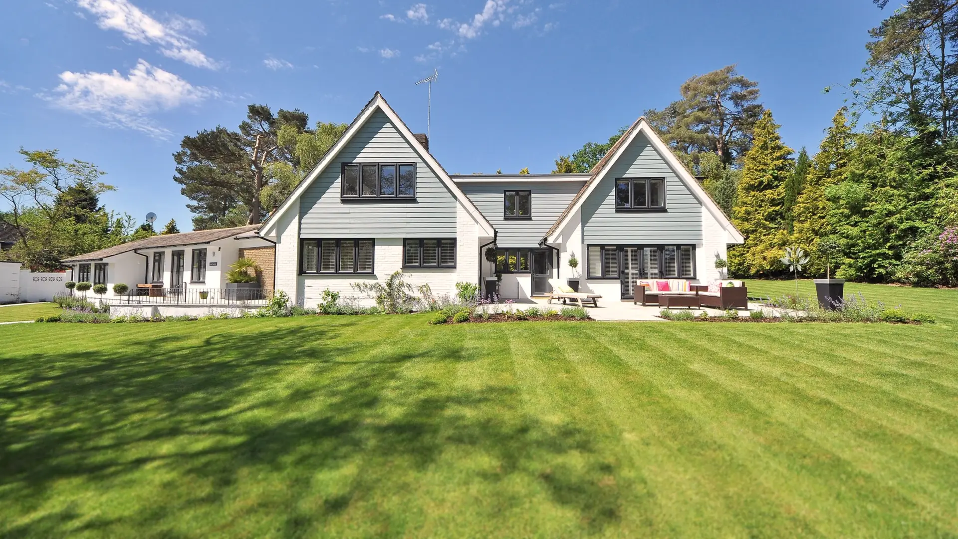 Wide striped lawn in front of a white two-gable house
