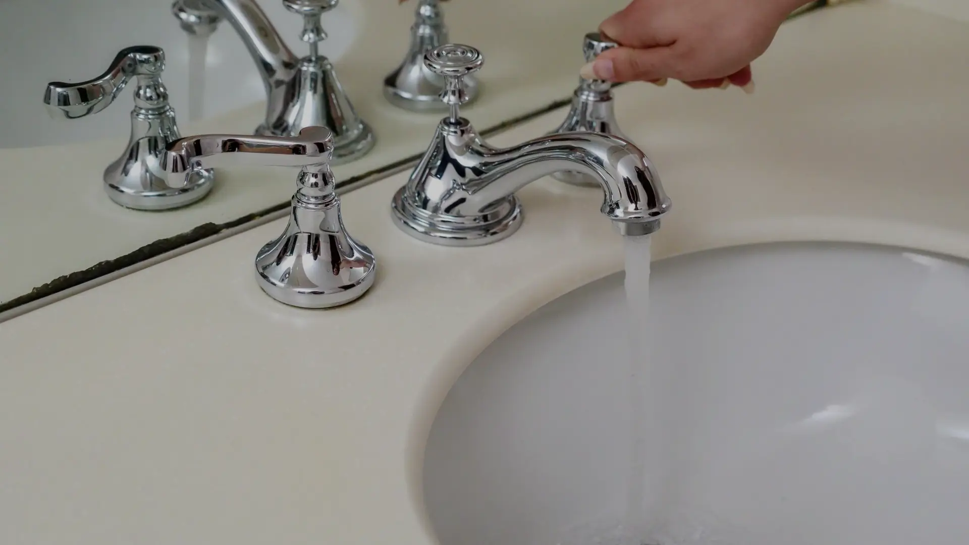 Water running from a chrome bathroom faucet into a clean sink