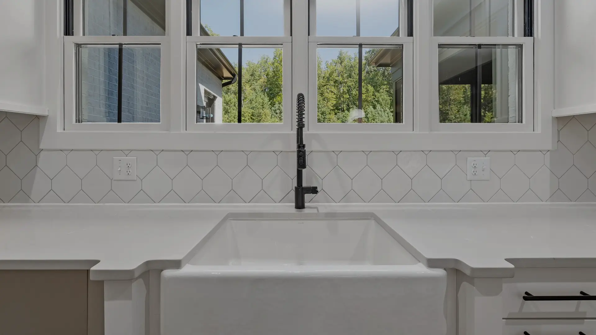 A dry, clean farmhouse kitchen sink under a row of windows