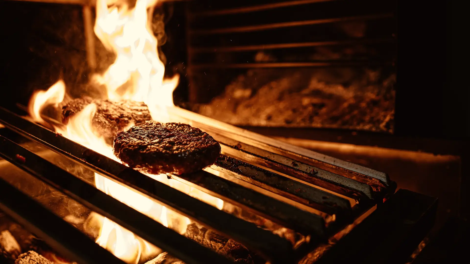 Meat searing on an iron grate over an open wood fire