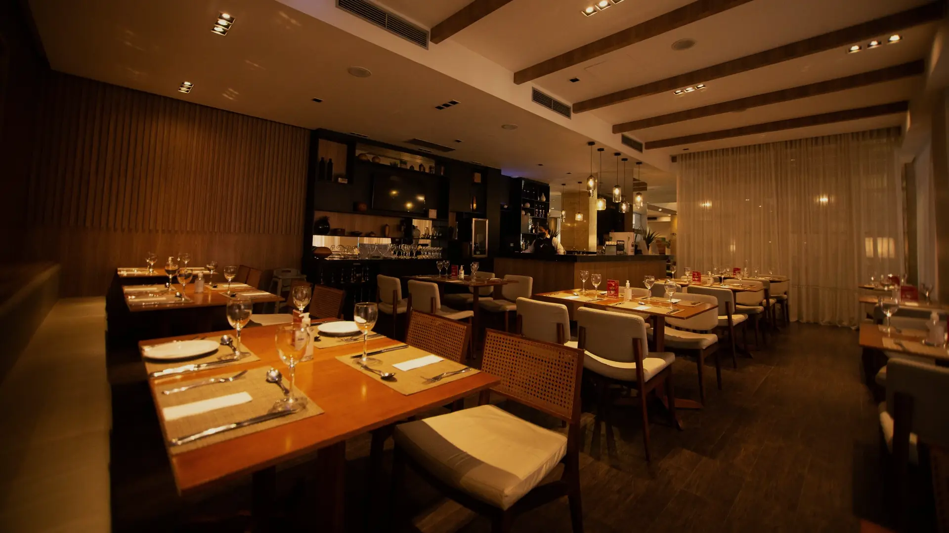The dining room set for dinner, warm lights over wood tables