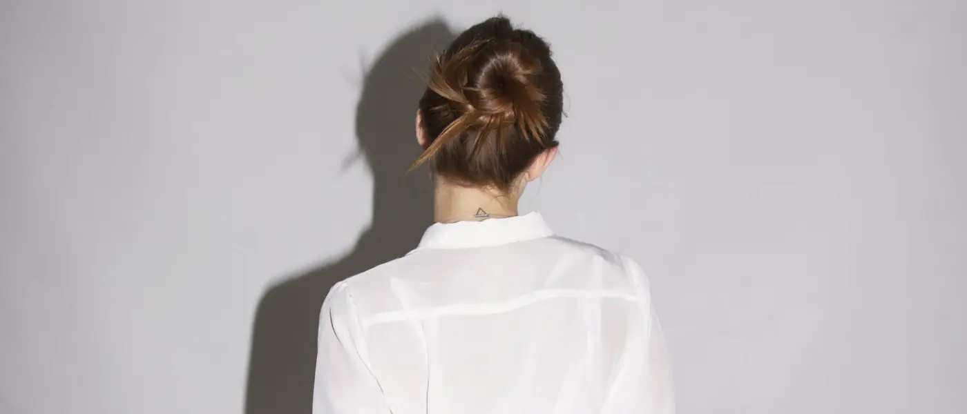A twisted low bun seen from behind against a pale gray wall